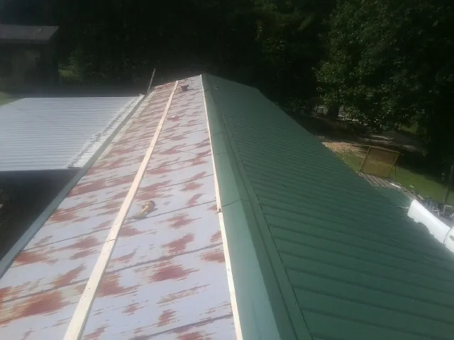Old rusted panels beside newly installed green metal roofing — Wind Damage Roof Repair by Roofing Brothers in Center Barnstead