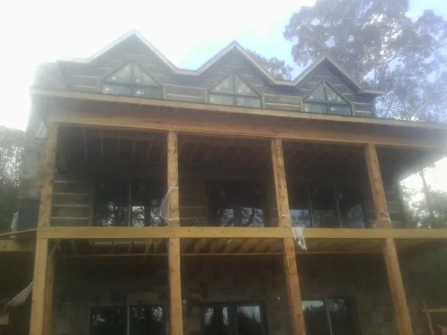 Dormers and porch framing on a large log home under construction — Roof Coating work by our crew in Center Barnstead