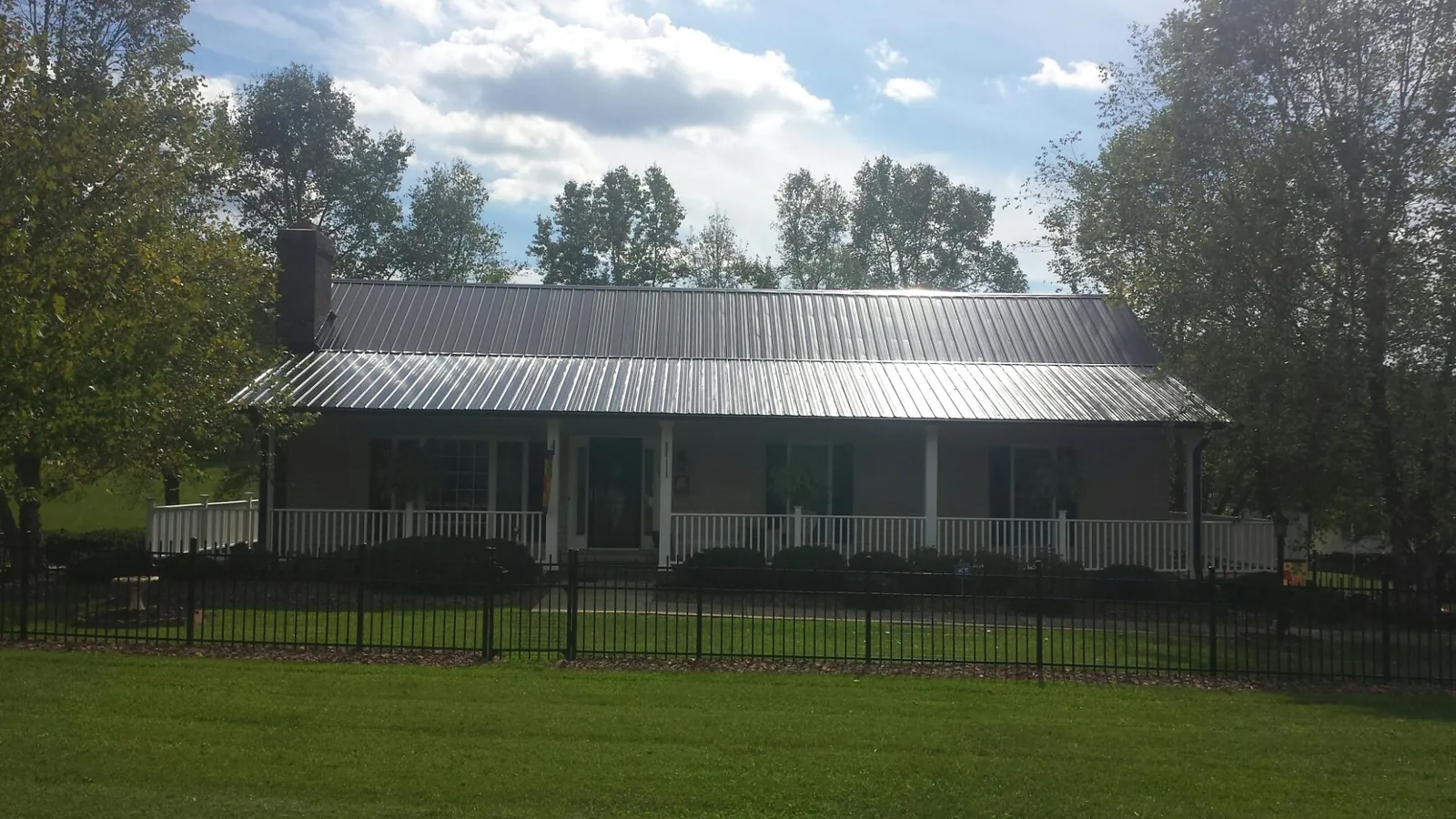Gray metal roof on a brick ranch with a full width front porch — Gutter Guard Installation work by our crew in Center Barnstead