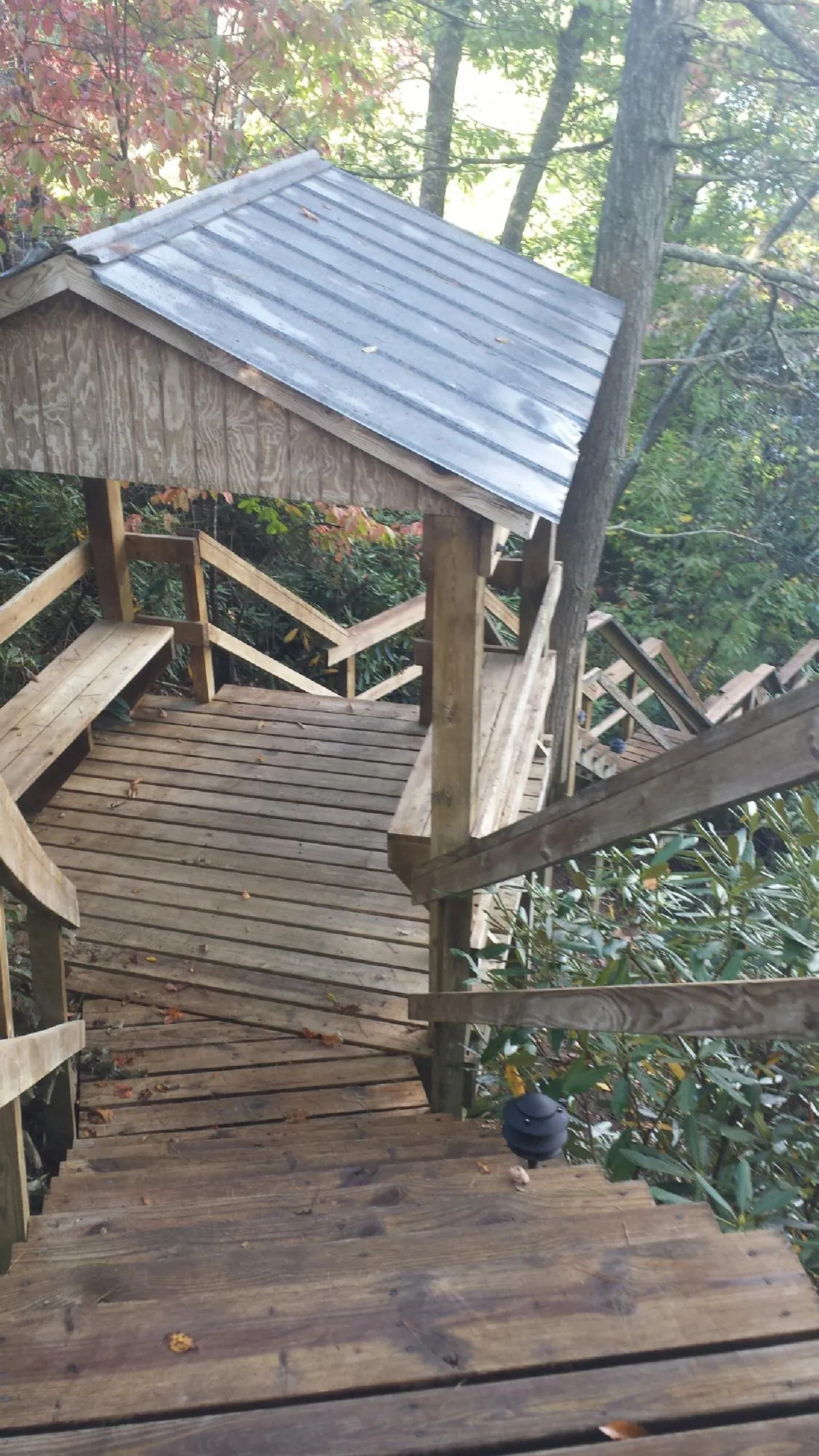 Metal roofed shelter over wooden steps on a wooded walkway — Skylight Repair & Installation work by our crew in Center Barnstead