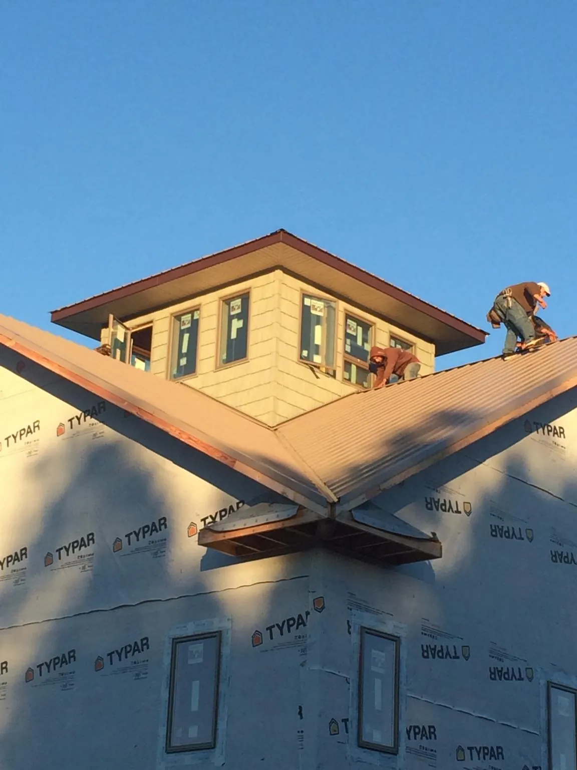Roofers working around a rooftop cupola on a new metal roof at sunset — Roof Waterproofing in Center Barnstead by Roofing Brothers